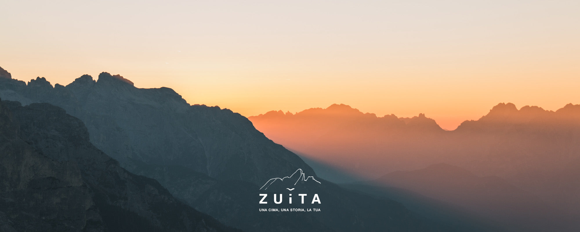 Tramonto tra le montagne e logo Zuita.